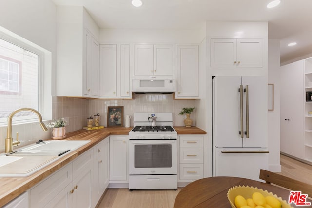 kitchen featuring white appliances, sink, tasteful backsplash, white cabinetry, and light hardwood / wood-style flooring