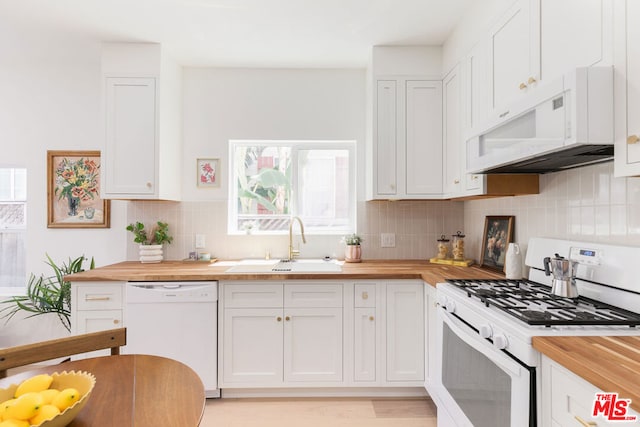 kitchen with white appliances, white cabinets, sink, butcher block countertops, and light hardwood / wood-style flooring