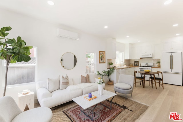 living room featuring sink, light hardwood / wood-style flooring, and an AC wall unit