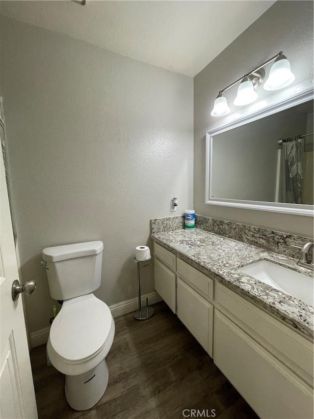 bathroom with curtained shower, vanity, toilet, and hardwood / wood-style flooring