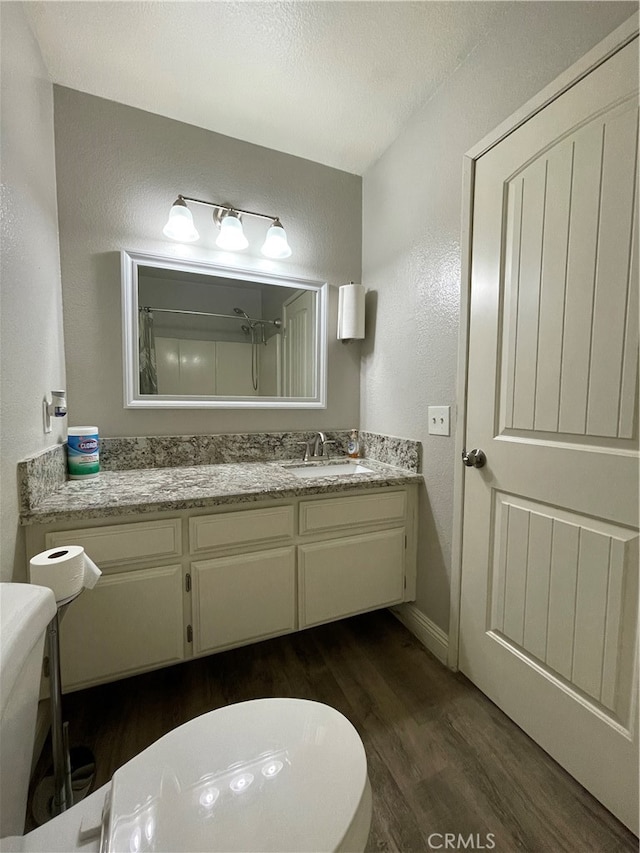 bathroom with a shower, vanity, a textured ceiling, toilet, and hardwood / wood-style floors