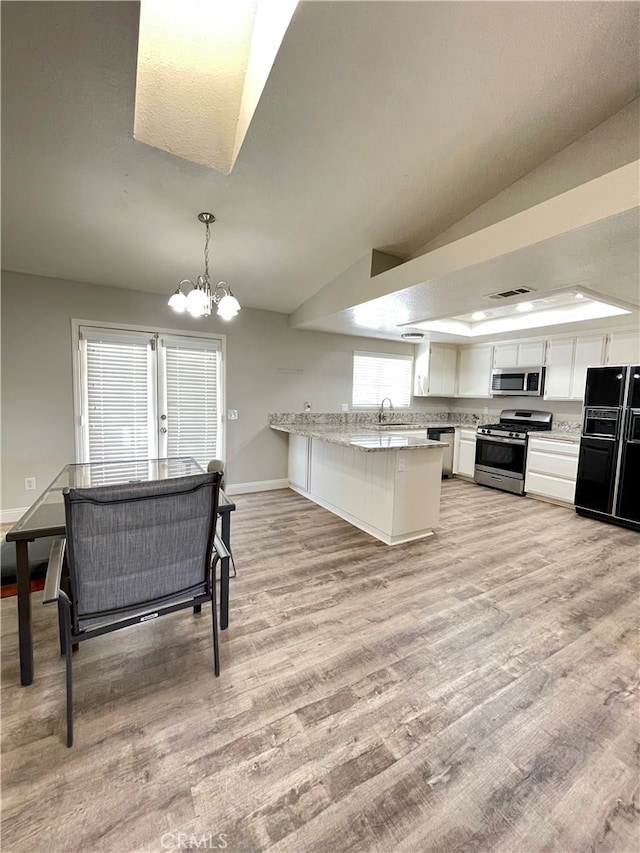 kitchen with pendant lighting, kitchen peninsula, light hardwood / wood-style flooring, white cabinetry, and stainless steel appliances