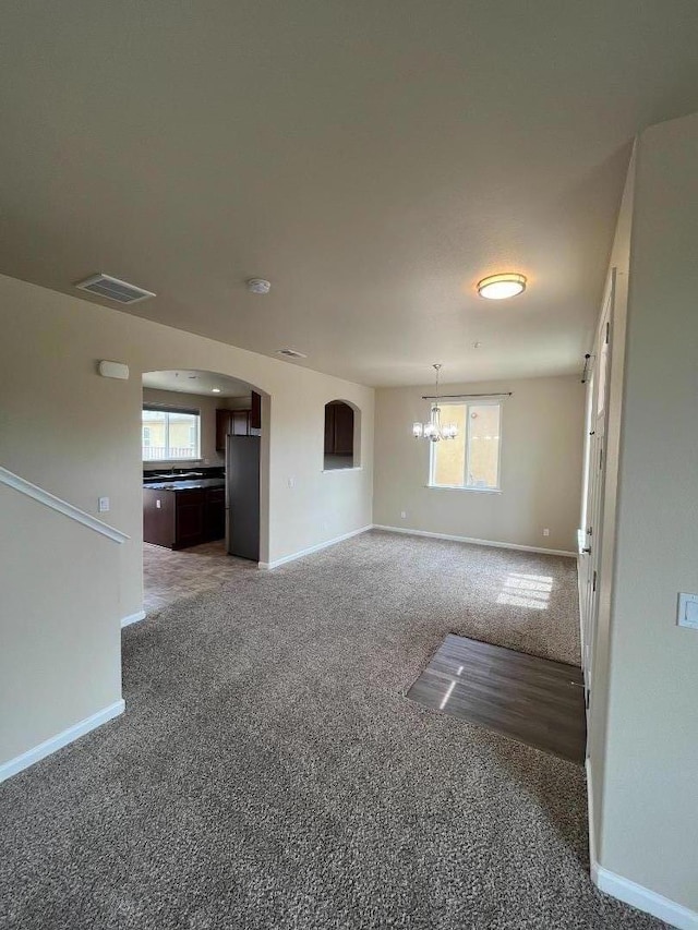 unfurnished living room featuring a chandelier and dark carpet