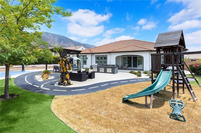 view of play area featuring outdoor lounge area, a mountain view, a yard, and a patio