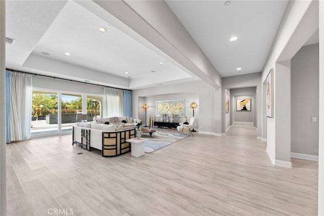 living room featuring a tray ceiling and light hardwood / wood-style flooring