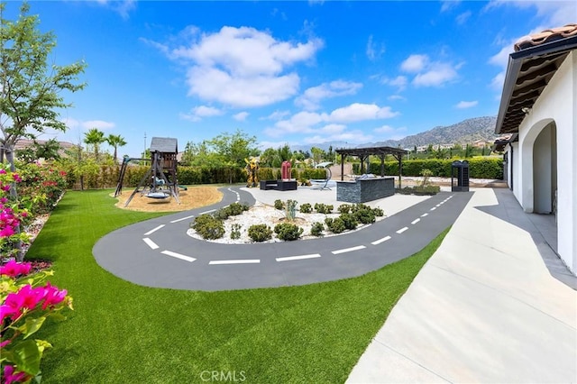 surrounding community with a lawn, a mountain view, a playground, and a pergola