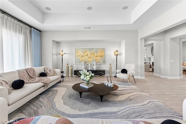 living room with a tray ceiling and light hardwood / wood-style flooring