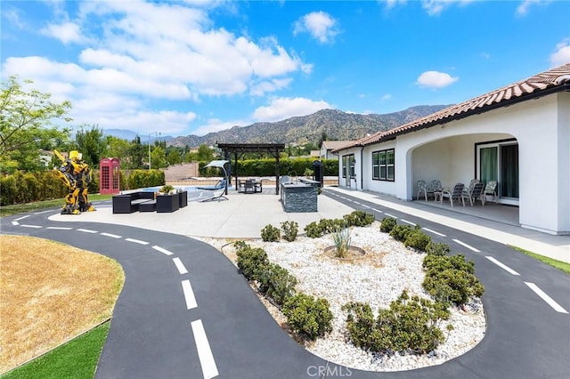 view of community with a mountain view, a pergola, an outdoor living space with a fire pit, and a patio area