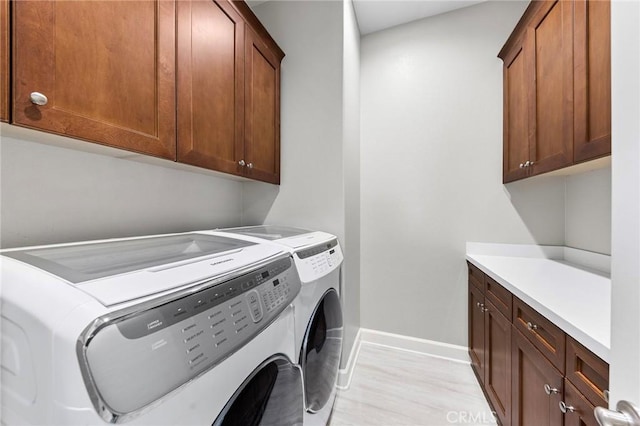 washroom featuring cabinets, light wood-type flooring, and washing machine and clothes dryer