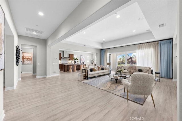 living room featuring a raised ceiling and light hardwood / wood-style flooring