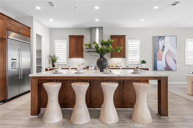 kitchen with stainless steel built in fridge, plenty of natural light, and a center island with sink