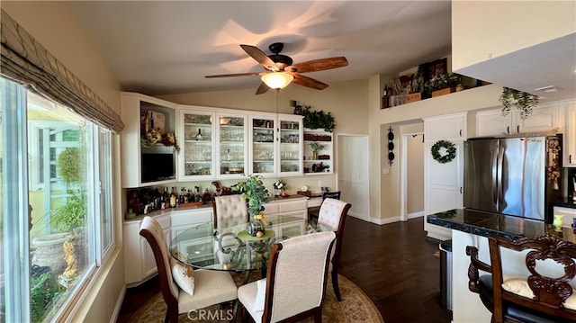 dining space with ceiling fan, vaulted ceiling, and dark wood-type flooring