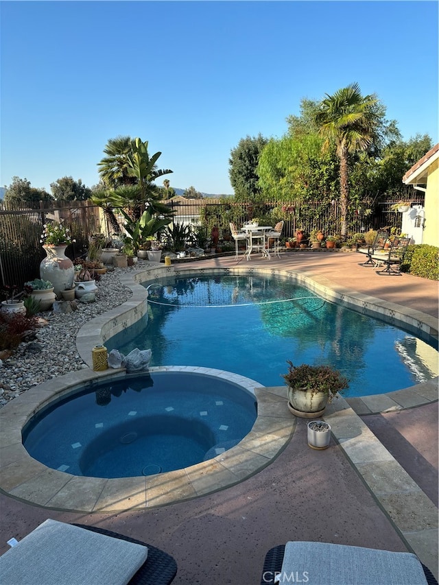 view of swimming pool featuring an in ground hot tub and a patio