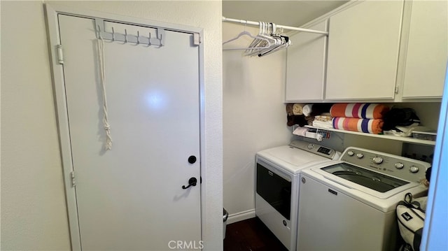 clothes washing area with independent washer and dryer, dark hardwood / wood-style flooring, and cabinets