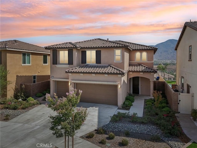 mediterranean / spanish house with a gate, fence, concrete driveway, and stucco siding