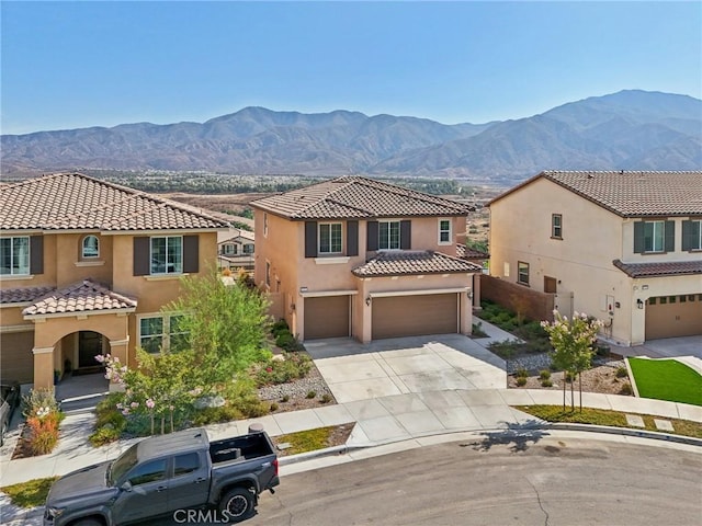 mediterranean / spanish-style home with driveway, a tiled roof, a mountain view, and stucco siding