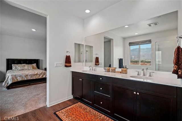 bathroom featuring visible vents, a sink, ensuite bathroom, and wood finished floors