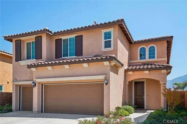 mediterranean / spanish-style home with a garage, fence, concrete driveway, and stucco siding