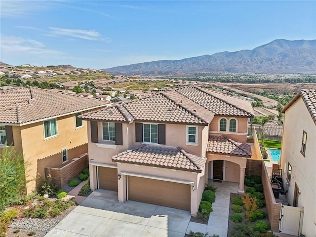 mediterranean / spanish house featuring a mountain view, driveway, fence, and stucco siding