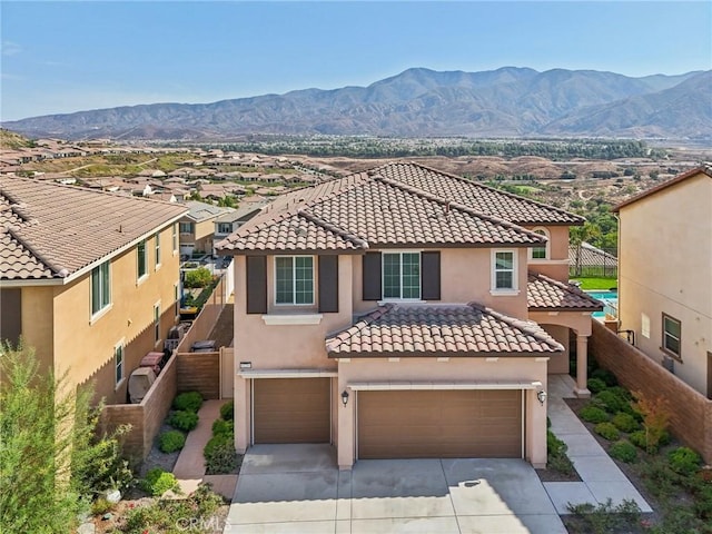 mediterranean / spanish-style home featuring driveway, fence, a mountain view, and stucco siding