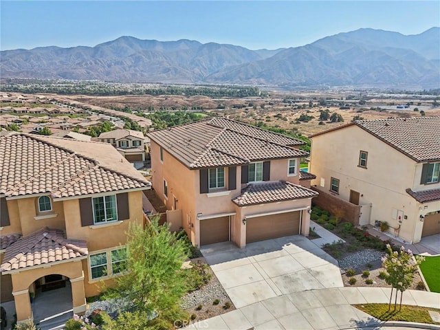 view of front facade with stucco siding, a mountain view, a residential view, driveway, and a tiled roof