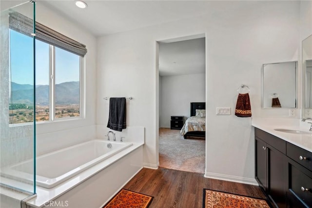 full bath featuring a garden tub, a mountain view, wood finished floors, vanity, and ensuite bath