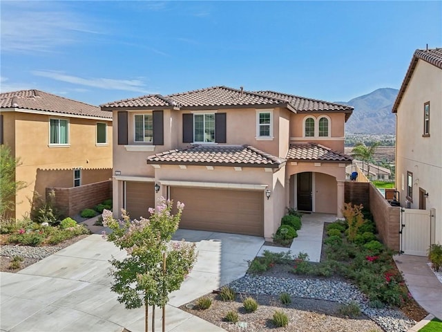 mediterranean / spanish home with a mountain view, fence, concrete driveway, a gate, and stucco siding