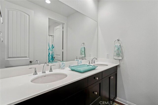 full bathroom with a sink, baseboards, and double vanity