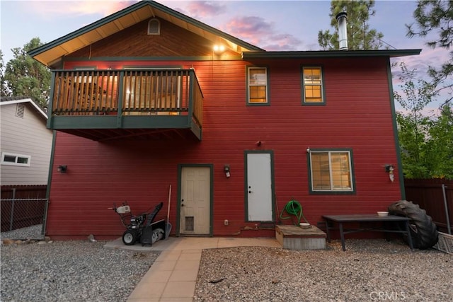 back house at dusk featuring a balcony