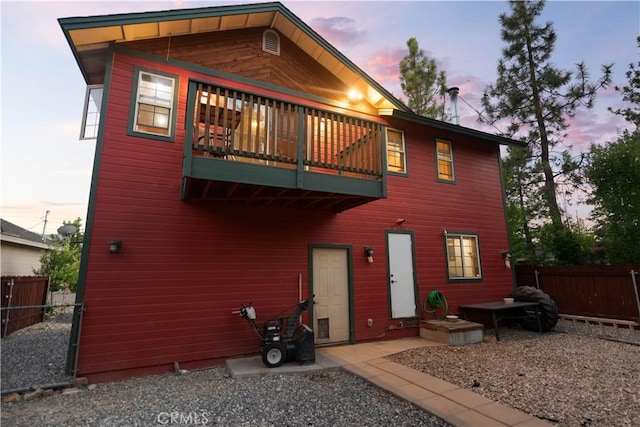 back house at dusk featuring a balcony