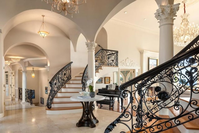 entrance foyer with decorative columns, crown molding, a towering ceiling, a chandelier, and light tile patterned floors