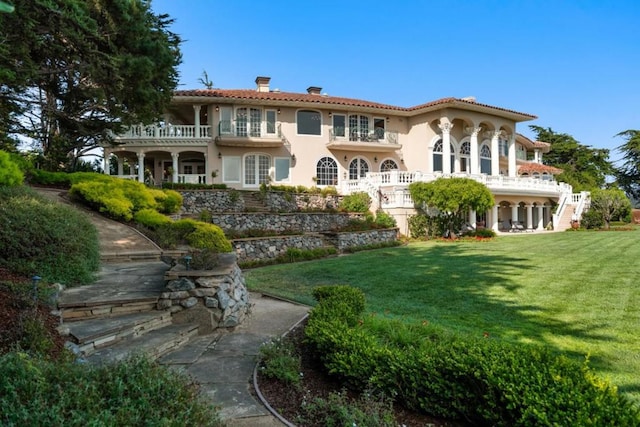 back of property featuring a balcony and a yard