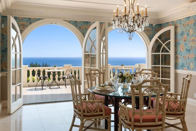 dining space featuring a water view, ornamental molding, and a chandelier