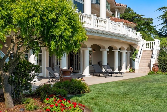 back of property with a yard, a balcony, and a patio