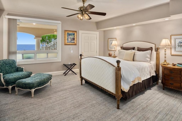 bedroom with carpet floors, ceiling fan, and a water view