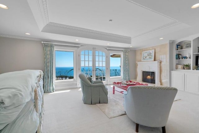 carpeted living room featuring a healthy amount of sunlight, a water view, ornamental molding, and a tray ceiling