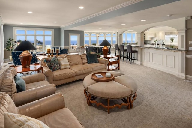 living room with ornate columns, crown molding, and light carpet