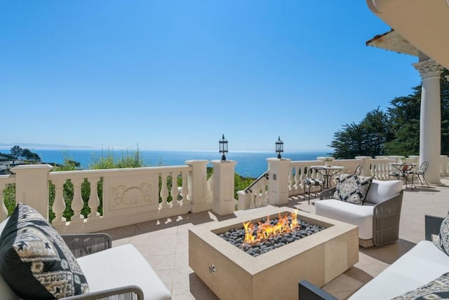 view of patio with a water view and an outdoor living space with a fire pit