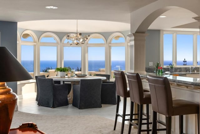 tiled dining room with a water view, an inviting chandelier, and sink