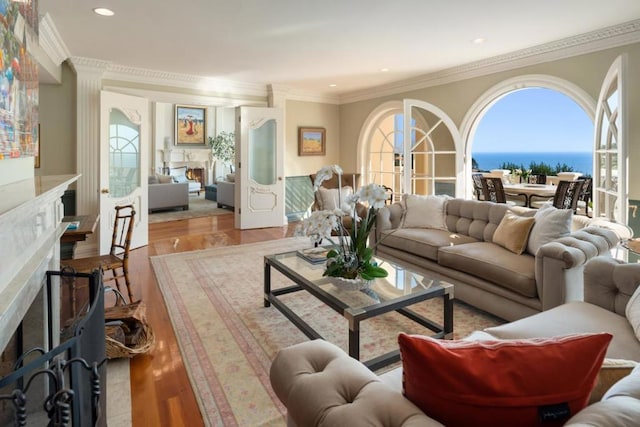 living room with ornamental molding, a water view, and light hardwood / wood-style floors