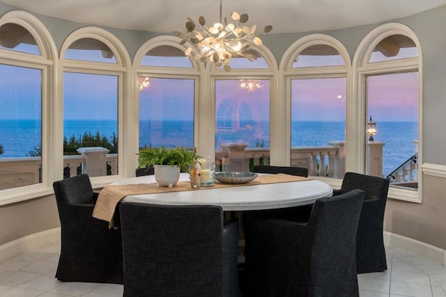 dining space with a water view, a chandelier, and light tile patterned floors