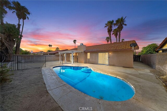 pool at dusk with a patio area