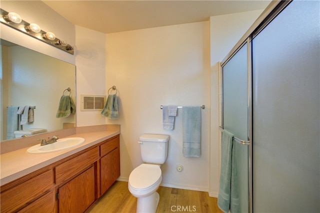 bathroom featuring wood-type flooring, vanity, walk in shower, and toilet