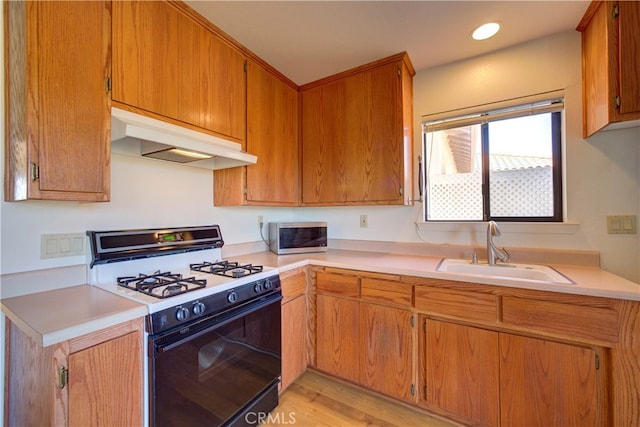 kitchen with light wood-type flooring, sink, and gas stove