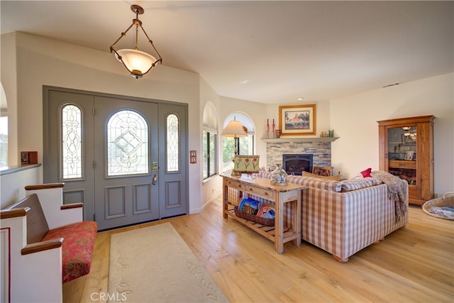 foyer entrance with light hardwood / wood-style floors and a fireplace