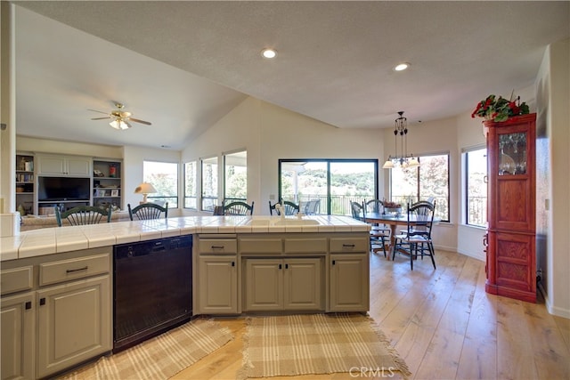 kitchen featuring light wood-type flooring, tile counters, lofted ceiling, and dishwasher