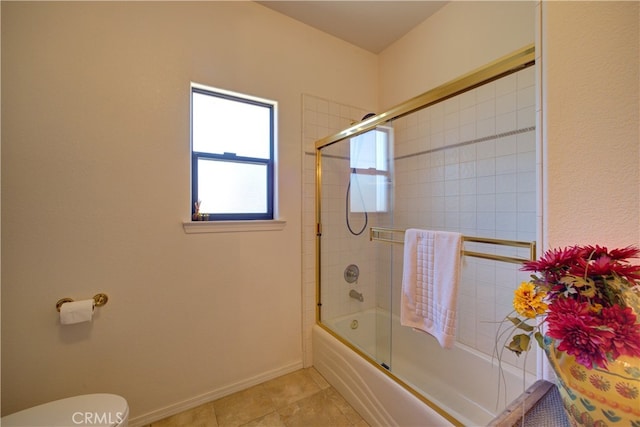 bathroom with tile patterned flooring, bath / shower combo with glass door, and toilet