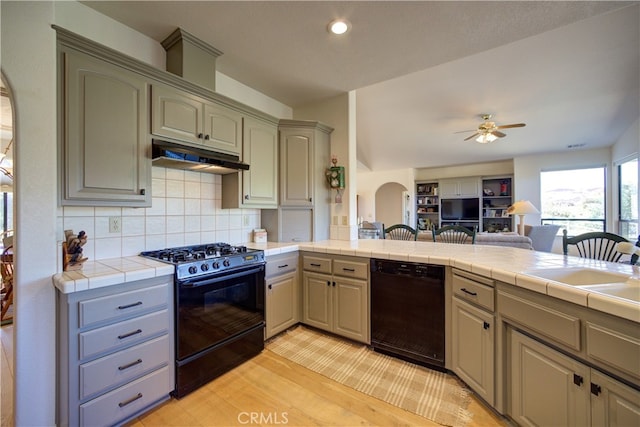 kitchen with tile counters, tasteful backsplash, light hardwood / wood-style flooring, black appliances, and ceiling fan