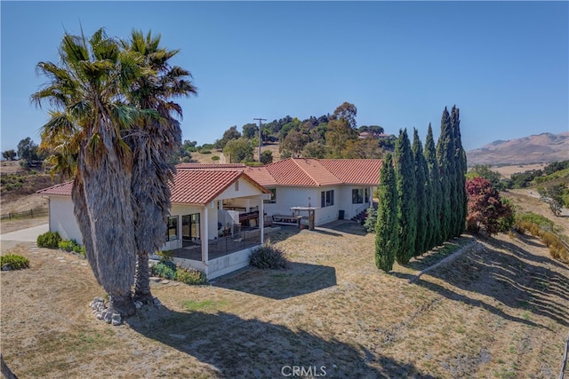 back of property with a mountain view and a lawn