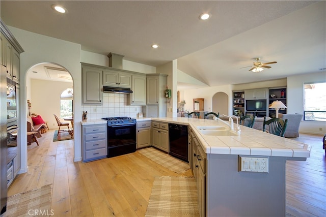 kitchen featuring sink, kitchen peninsula, black appliances, tile countertops, and light hardwood / wood-style floors